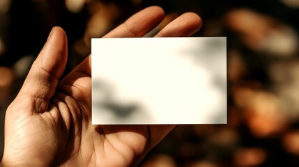 Obraz premium A hand holding a blank card against a blurred background.