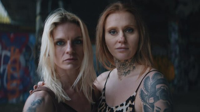 Two Women With Tattoos Conveying Serious Emotions