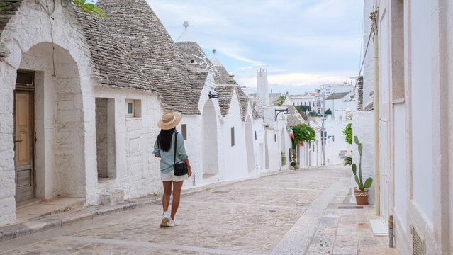 Fototapeta Strolling through the picturesque, whitewashed streets of Alberobello Puglia, a traveler admires the iconic trulli architecture under a softly lit sky. The tranquil atmosphere invites exploration.