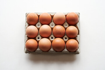 Fresh brown eggs arranged neatly in a carton on a clean white background