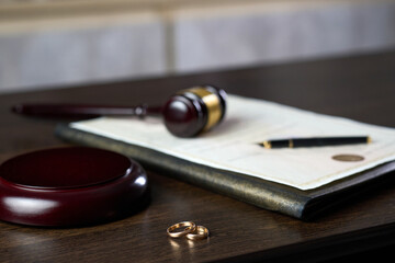 Divorce and separation concept. Judge gavel with wedding rings and divorce decree. Marital agreement, legalities of divorce