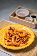 still life, shrimps on a yellow plate, spices and sauce behind them