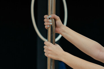 Detalle de brazo de mujer caucásica en barra de pole dance.