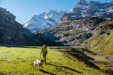 Woman with dog in Switzerland mountain valley Kiental, Berner Oberland Alps. Snow mountains, sunny weather, travel to Swiss, travelling with pet.