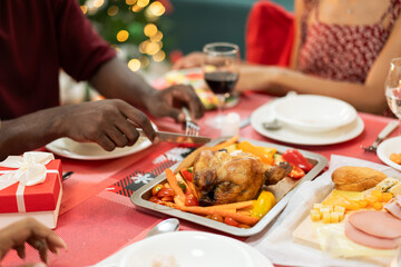 Family having Christmas dinner together at home. People drinking, eating and enjoy talking at dining table. Festive celebration party with delicious feast on holidays.