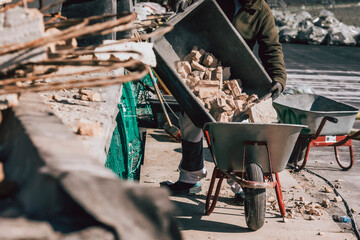 Bauarbeiter kippt Steine in Schubkarre