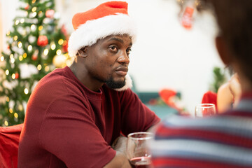 African family or friend enjoy talking during festive celebration on Christmas party at home. People wearing a christmas costume during the event.