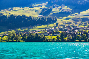 Swiss village Lungern with traditional houses, old church Alter Kirchturm along lovely emerald green lake Lungerersee, canton of Obwalden Switzerland