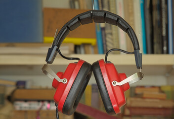 audio book concept with row of books and vintage headphone,blurred bookshelf background.Education,inspiration,relaxation,literature