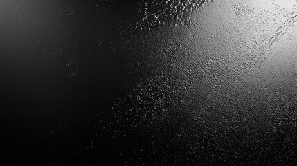A close-up of a textured black surface with droplets of water, creating an intriguing abstract effect.