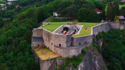 Aerial view of the Citadel of Dinant, Belgium, with its Belgian flag waving in the wind. Tourists visit the historical fortress - Powered by Adobe