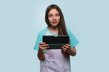Fototapeta premium Surprised young girl holding tablet, showing shocked expression.