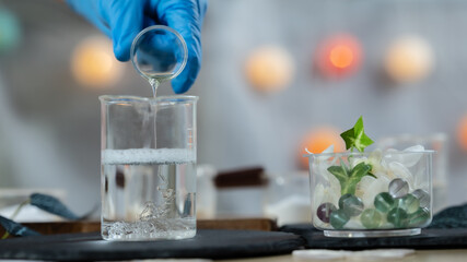 Scientist Pouring Liquid into Beaker in Cosmetic or Skincare Laboratory. A close-up image of a lab setup where a person wearing blue gloves is carefully pouring a clear liquid into a beaker, symbolizi