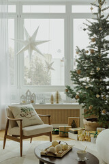 Bright holiday window view. A cozy armchair by the window with a beautiful view of a snowy Christmas tree, star ornaments, and wrapped gifts beneath.