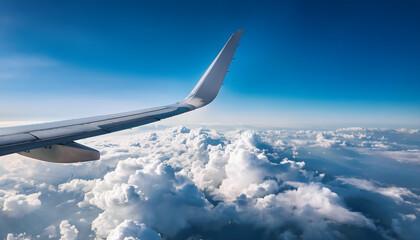 Obraz premium View from the side of a passenger plane flying high above white clouds and blue sky