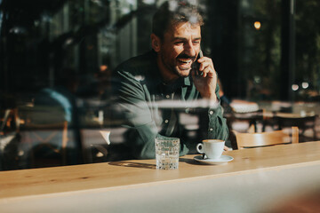 Toughtful man savoring coffee alone at a cozy cafe on a sunny day while lost in contemplation by the window
