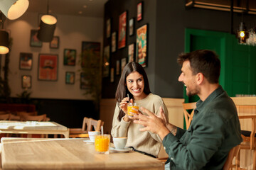 Couple enjoying at a cozy cafe with warm drinks and laughter in a vibrant, modern setting on a sunny afternoon