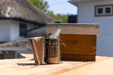 Beekeeping equipment sitting on a wooden surface, ready for a beekeeper to use for hive...