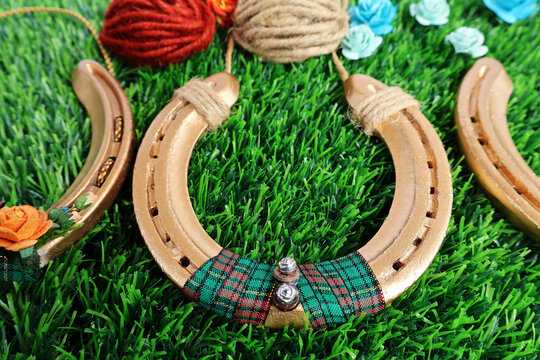Used horseshoes spray painted gold yellow decorated with ribbons. Wrapped with hemp rope for hanging and artificial flowers. Placed on green artificial grass
- Powered by Adobe