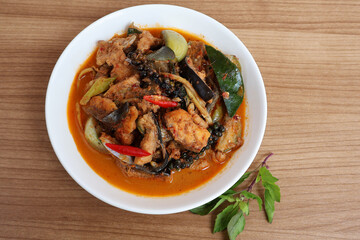 Stir-fried spicy giant catfish, seen above Place the basil tops next to the plate on the wooden table.

