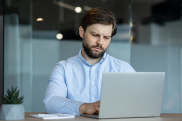 Focused businessman working on a laptop in modern office