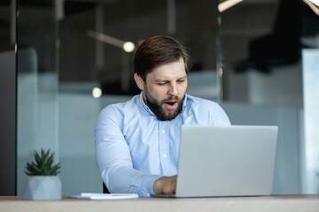 Tired office worker yawning at desk with laptop