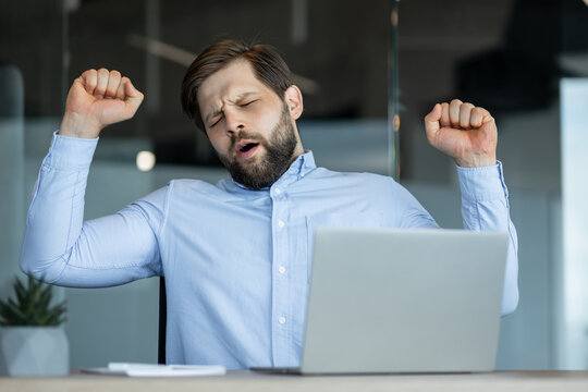Businessman feeling tired and yawning during work in office