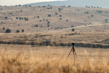 A lonely camera on tripod in the middle of dry desert-like field in spanish country