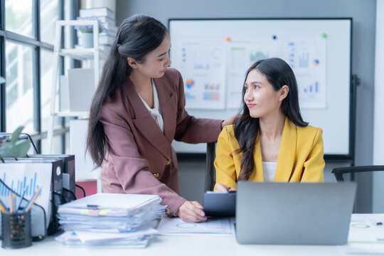 Businesswoman is comforting her upset colleague by putting a hand on her shoulder while looking at her with compassion