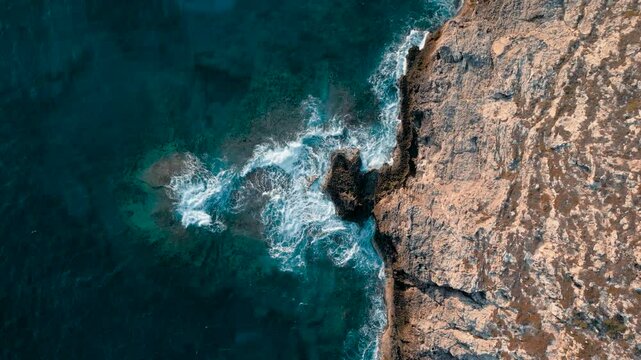 Aerial 4k video of a cliff at sunrise with the waves crushing onto it, Lampedusa, Italy