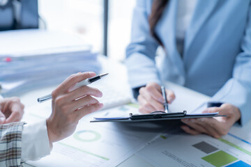 Two businesswomen collaborating in an office meeting, analyzing financial documents and strategizing for success