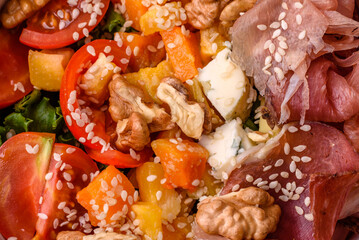 Appetizing salad with prosciutto, pumpkin, cheese and tomatoes