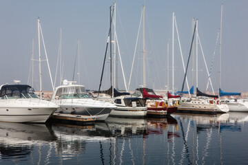 Docked sailboats and power boats cast a reflection on the calm harbor waters of Egg Harbor, Door County, Wisconsin on a late spring morning.