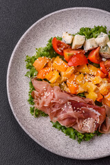 Appetizing salad with prosciutto, pumpkin, cheese and tomatoes