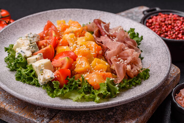Appetizing salad with prosciutto, pumpkin, cheese and tomatoes