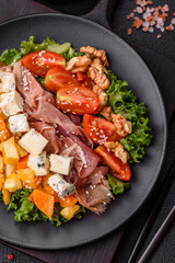 Appetizing salad with prosciutto, pumpkin, cheese and tomatoes