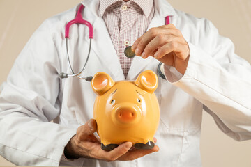 Close-up doctor holding a piggy bank in his hands, depositing money in a piggy bank, medical insurance savings, treatment price, health, medicine price, social security