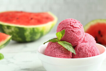 Scoops of tasty watermelon sorbet with mint in bowl on white table, closeup