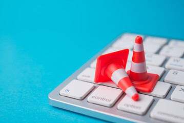 Maintenance, repair, under construction in computer system from virus or ransomware concept. Close up orange white traffic warning cones or pylon on white keyboard computer with copy space.
