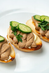 Savory canapes topped with creamy spread and cucumber slices served on toasted bread at a casual gathering