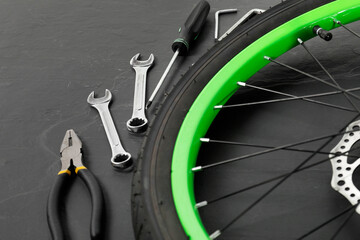 Fototapeta premium Bicycle wheel and tools on black background, closeup