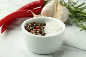 Sea salt, peppercorns, rosemary, chili peppers and garlic on white marble table, closeup