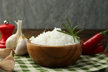 Sea salt in bowl and spices on table, closeup