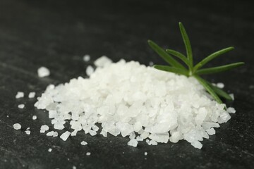 Sea salt and rosemary on dark gray textured table, closeup