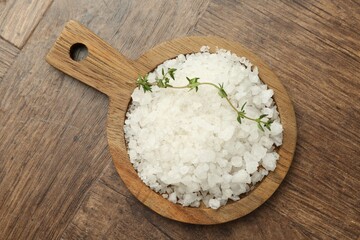 Sea salt and thyme on wooden table, top view