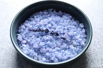 Natural sea salt and lavender flower on grey table, closeup