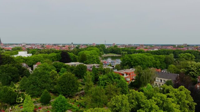 Camera moving forward over the city of Munster in germany. Lush green trees surround the Aasee Lake with its colorful boats