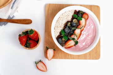 Presented by fruits putting yogurt toppings with strawberry, berry, oats, raisins and chia seed decorated by peppermint in white blow. Pink background. Set of healthy dairy product choice. Pecuniary.