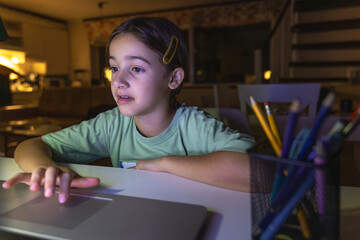 Beautiful girl studies at the computer at night. Technology and education.