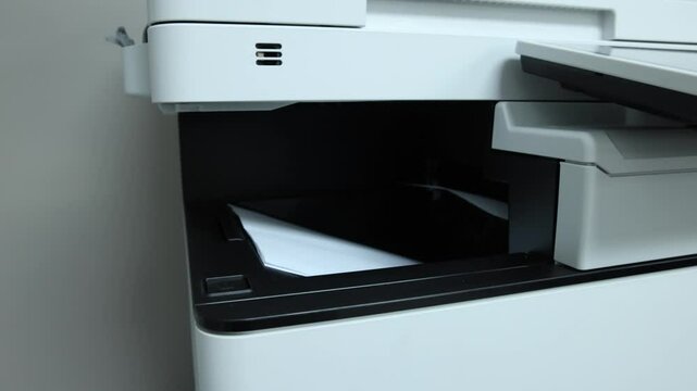 Printer slowly outputs paper in an office setting, showcasing modern technology in action. Selective focus
